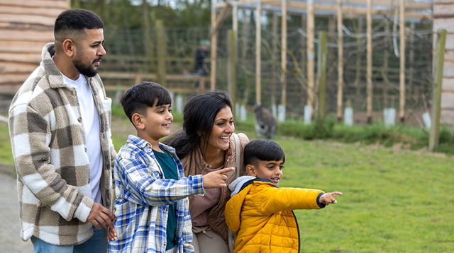 A wide shot of a family of four walking through various enclosures together at a zoo in Northumberland